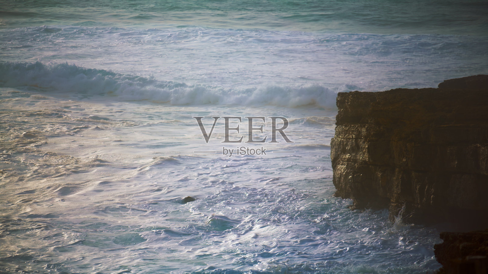 汹涌的海浪翻滚着悬崖海岸。泡沫飞溅的海洋冲刷着岩石海岸照片摄影图片