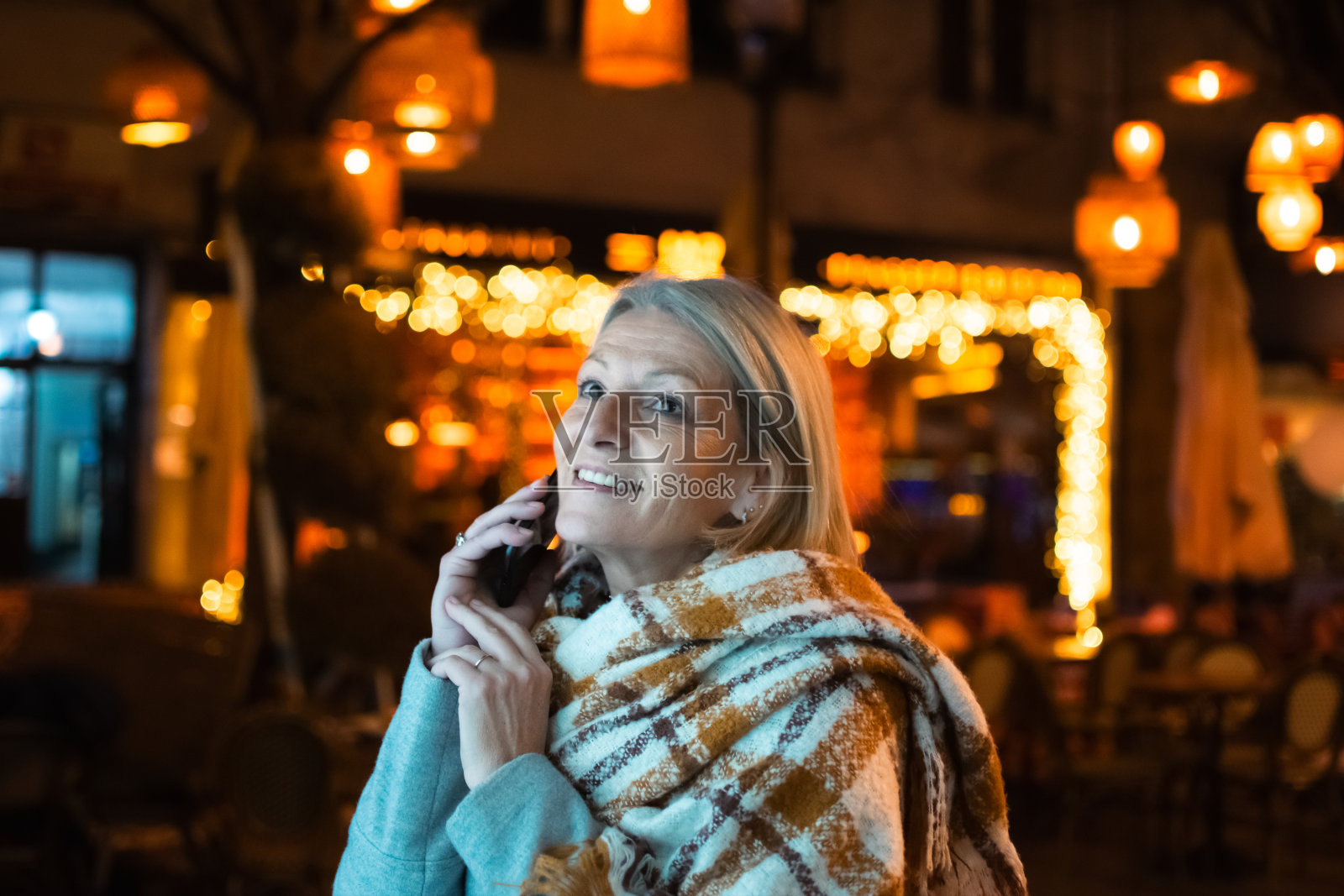 成熟的金发女游客在夜晚的城市街道上照片摄影图片