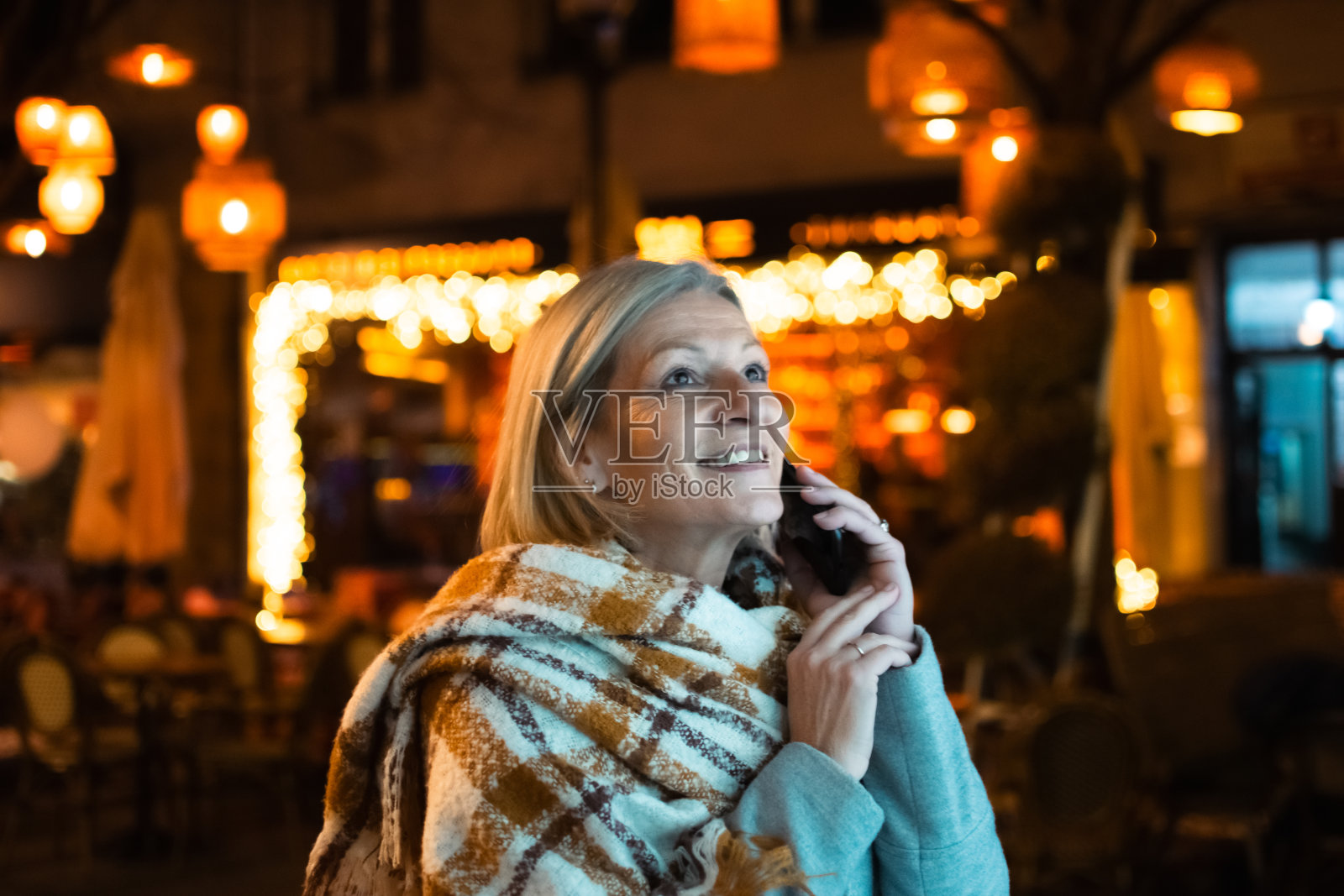 成熟的金发女游客在夜晚的城市街道上照片摄影图片