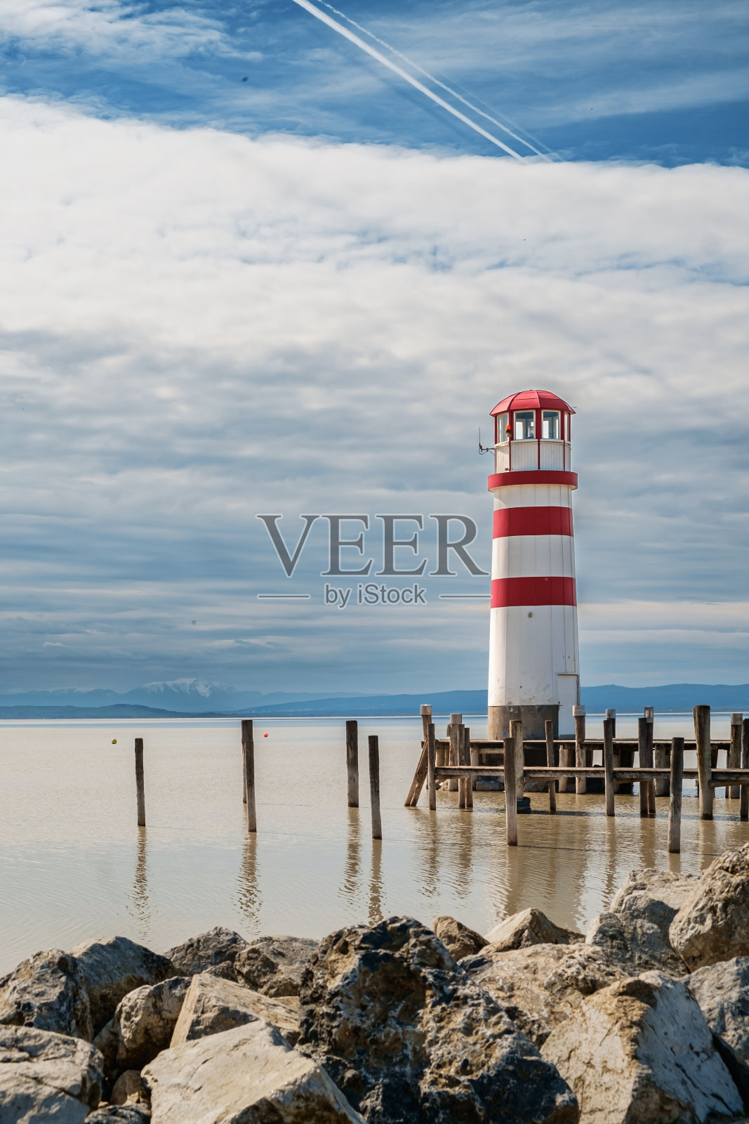 湖堤上的岩石和码头上的灯塔照片摄影图片