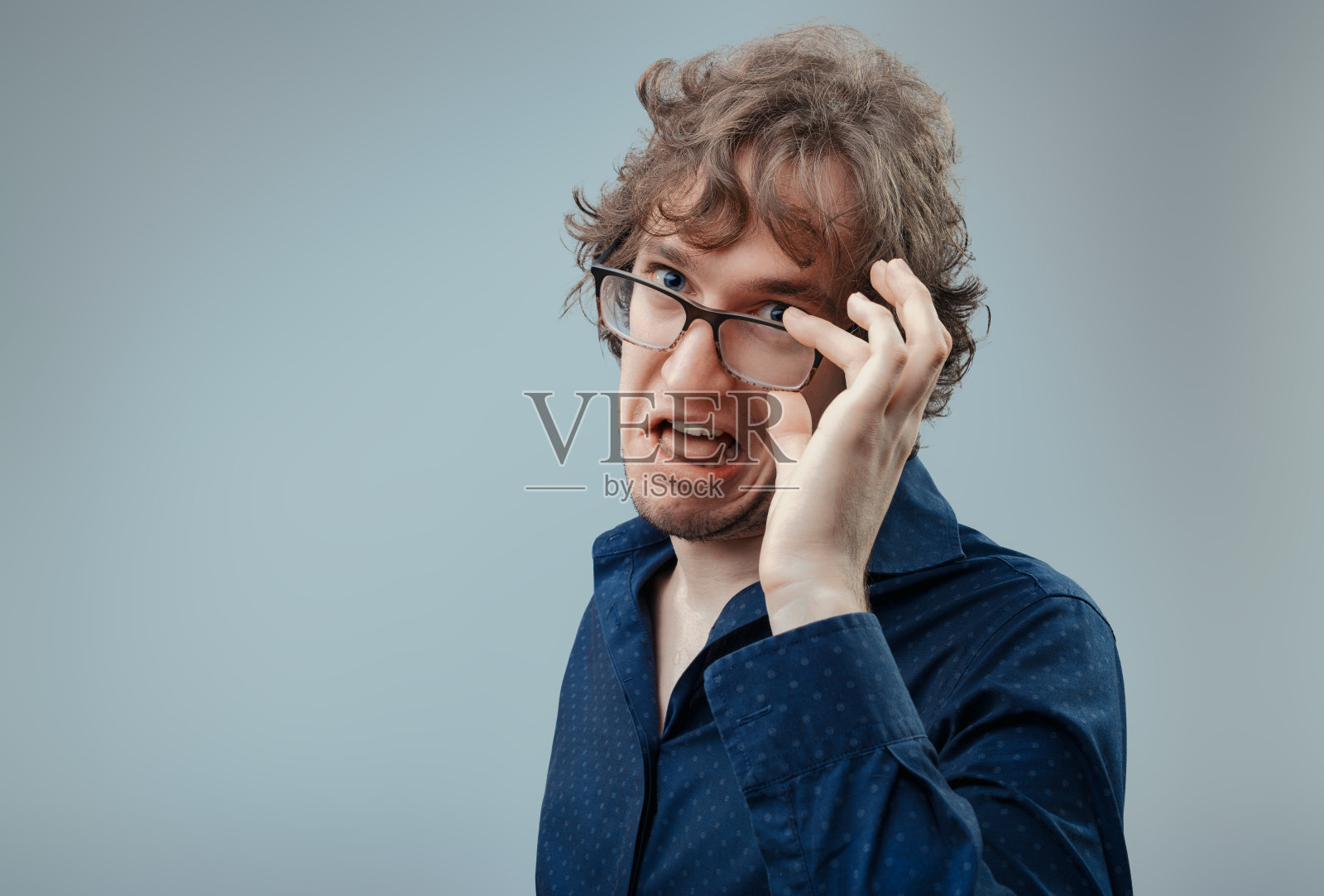 男人不高兴,戴着调整过的眼镜做了个鬼脸照片摄影图片