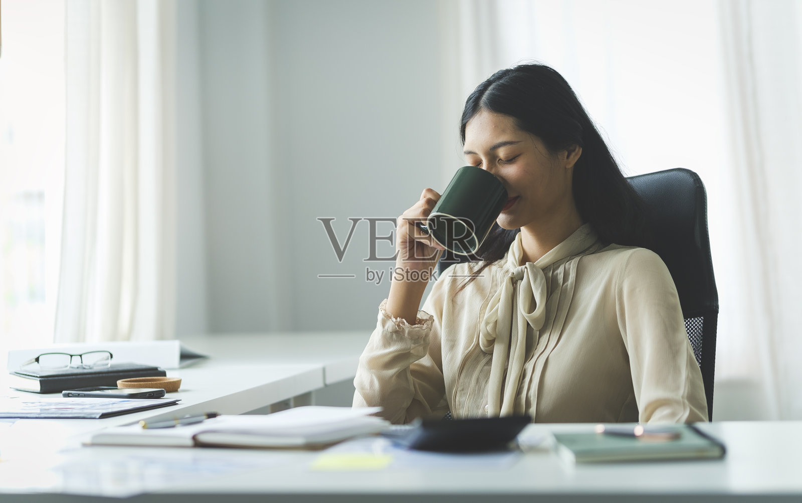 在现代化的办公室里,工作之余喝咖啡的女商人。照片摄影图片