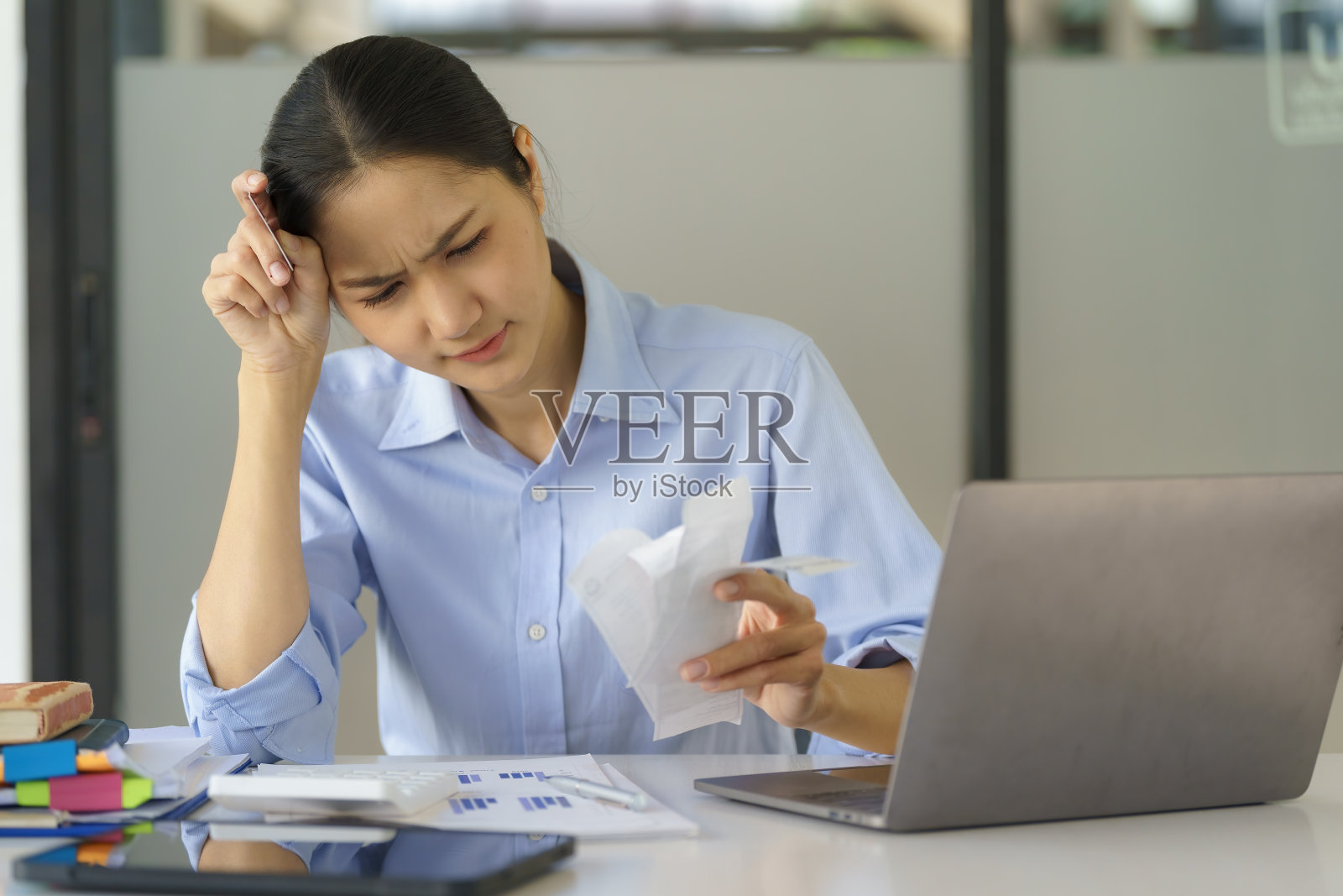 一位亚洲女商人为她的开支账单感到压力。照片摄影图片
