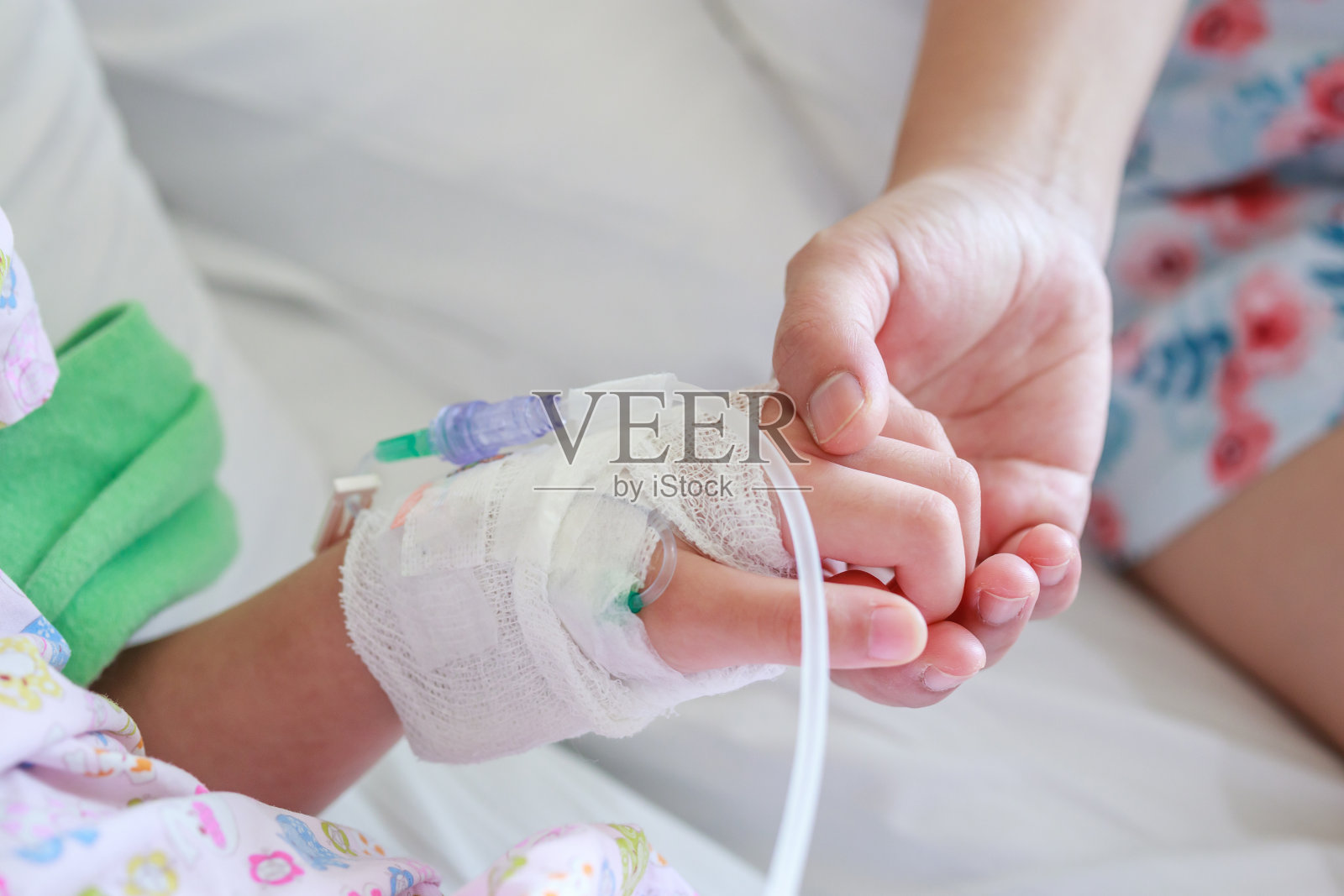 医院里,母亲用生理盐水牵着孩子的手照片摄影图片