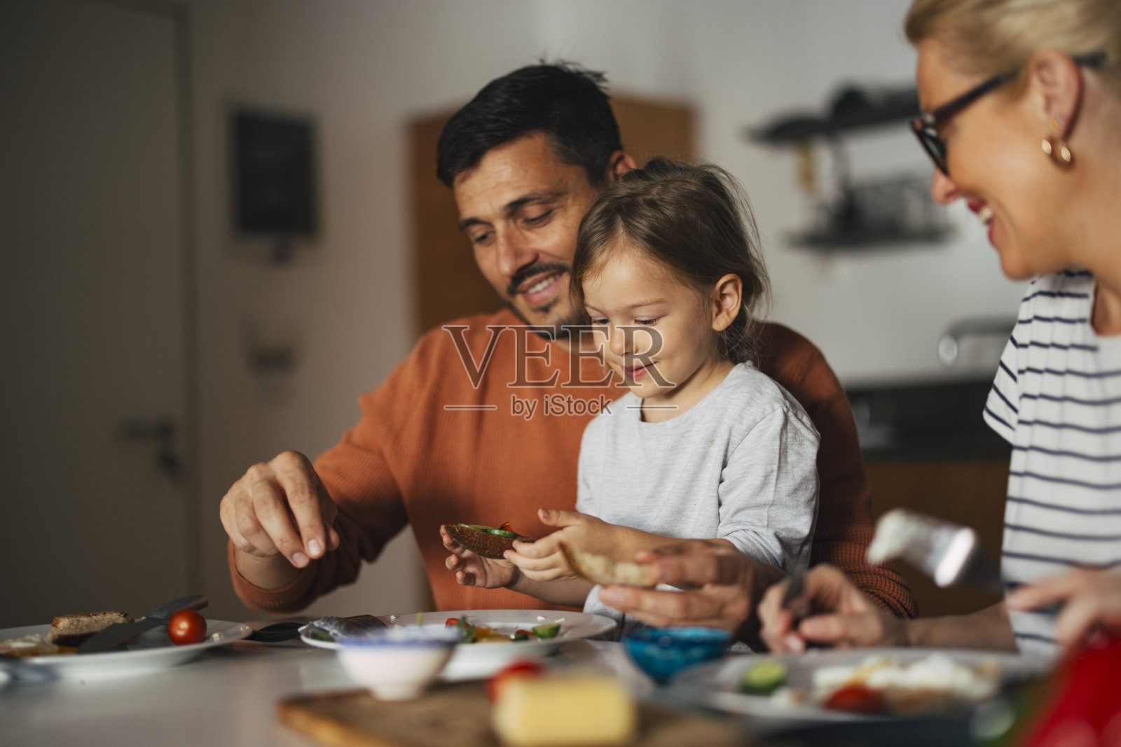 一个快乐的小女孩在家里和爸爸妈妈一起吃早餐的肖像照片摄影图片