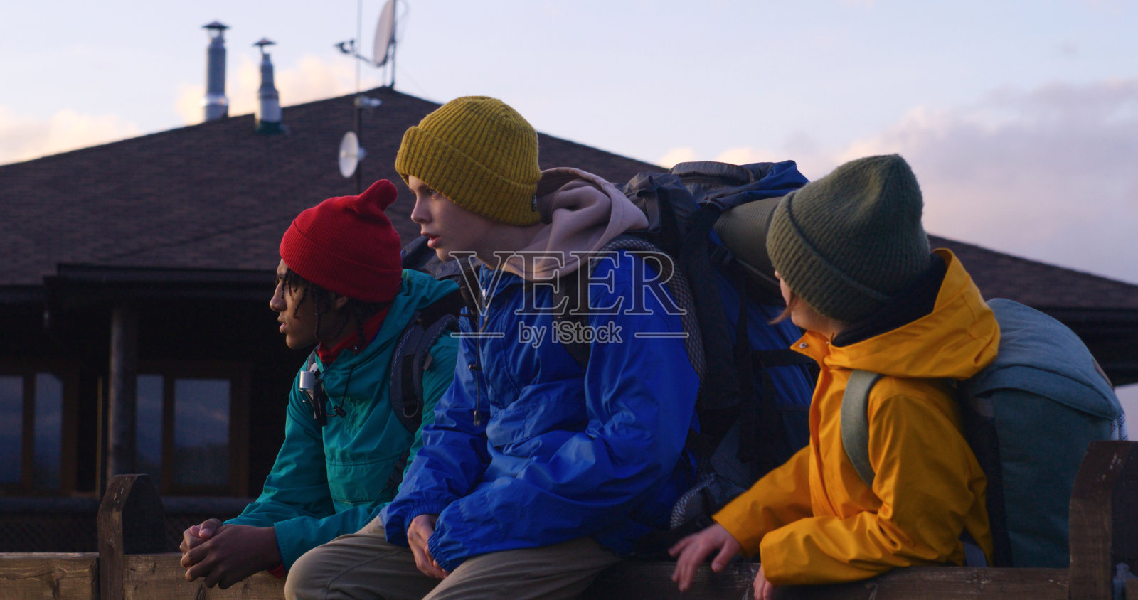 不同的年轻旅行者在栅栏附近看日落和山景照片摄影图片