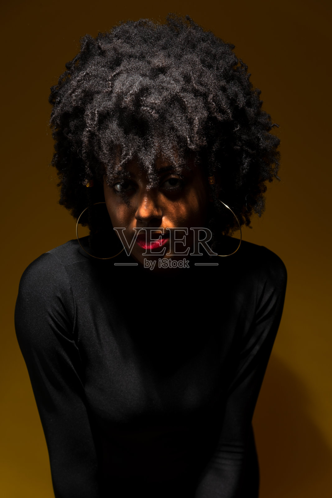 半封闭的年轻女子肖像,黑色的权力头发,穿着黑色的衣服与低光照片摄影图片