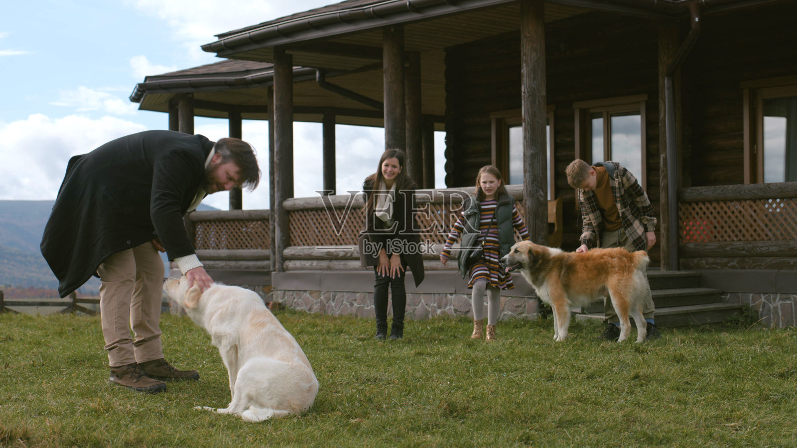 夫妇带着孩子在房子附近散步,在草坪上和狗玩耍照片摄影图片