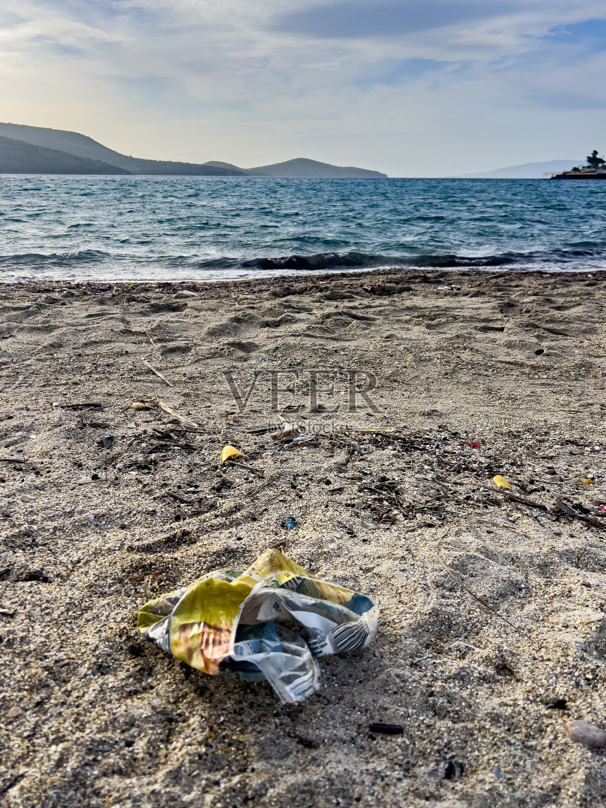 被丢弃在海边沙滩上的包装废弃物。照片摄影图片