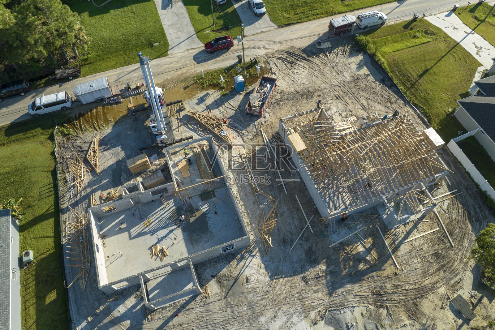 佛罗里达州农村地区,专业建筑商和起重机正在为未完工的郊区木结构房屋屋顶施工。美国的住房发展概念照片摄影图片