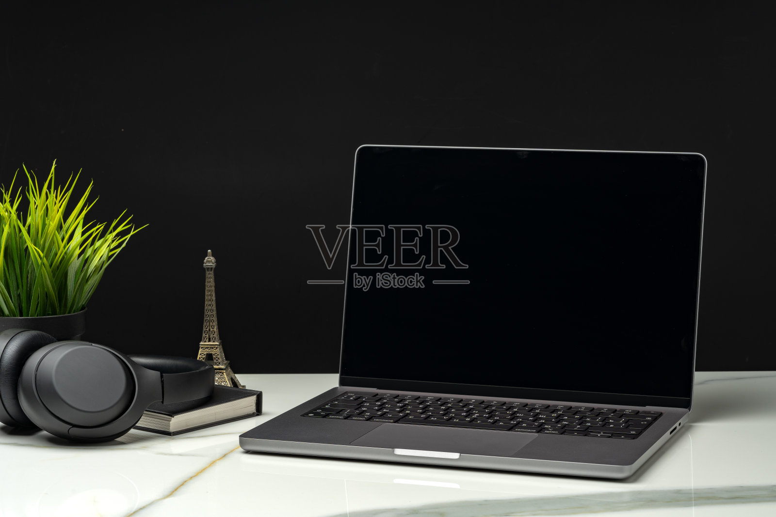 笔记本电脑与绿色叶盆栽在黑色背景照片摄影图片