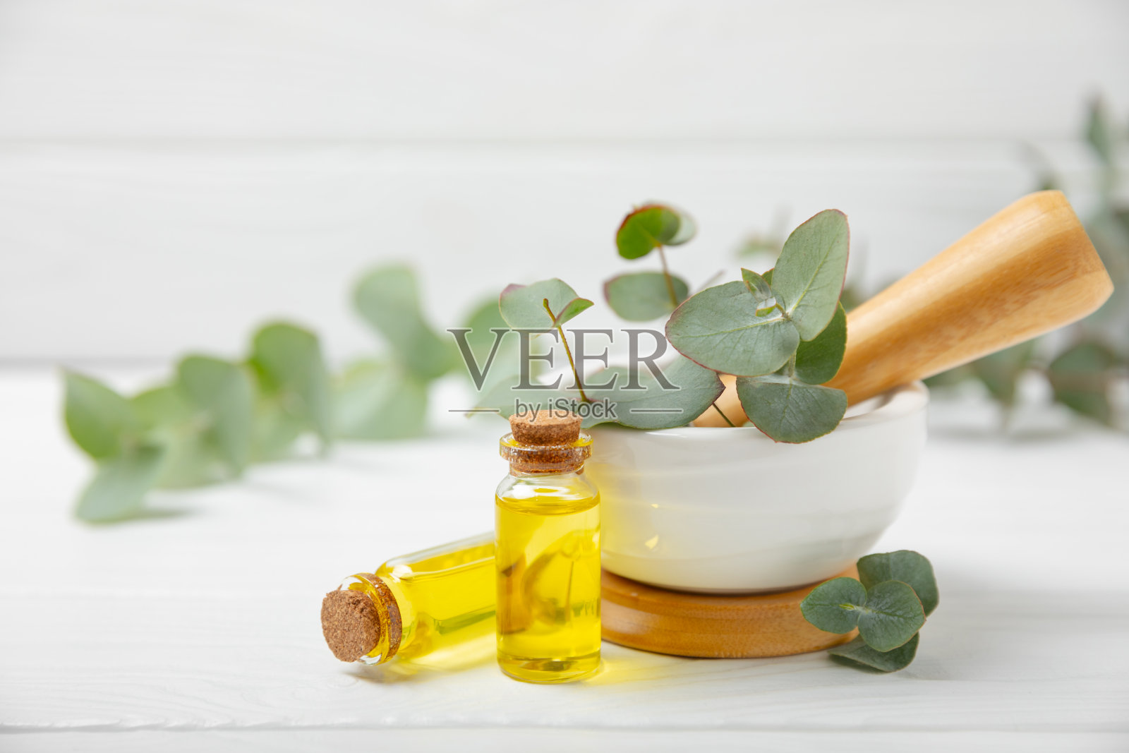 木质背景上的桉树叶和灰浆。水疗中心的概念。替代药物和天然化妆品成分。一瓶精油和一些桉树。有机护肤照片摄影图片