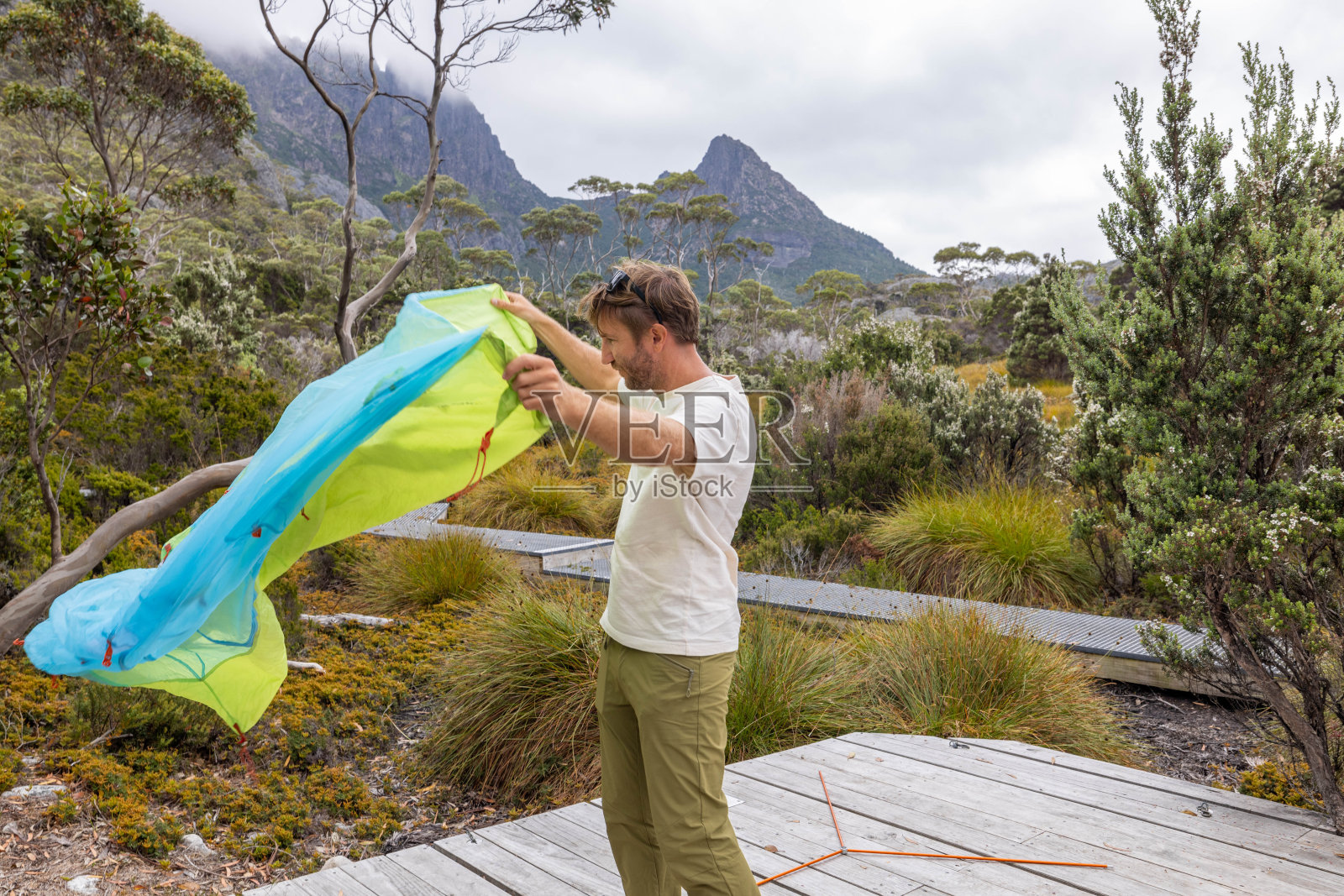 荒野静修:在塔斯马尼亚宁静的风景中,一名男子在木平台上搭帐篷照片摄影图片