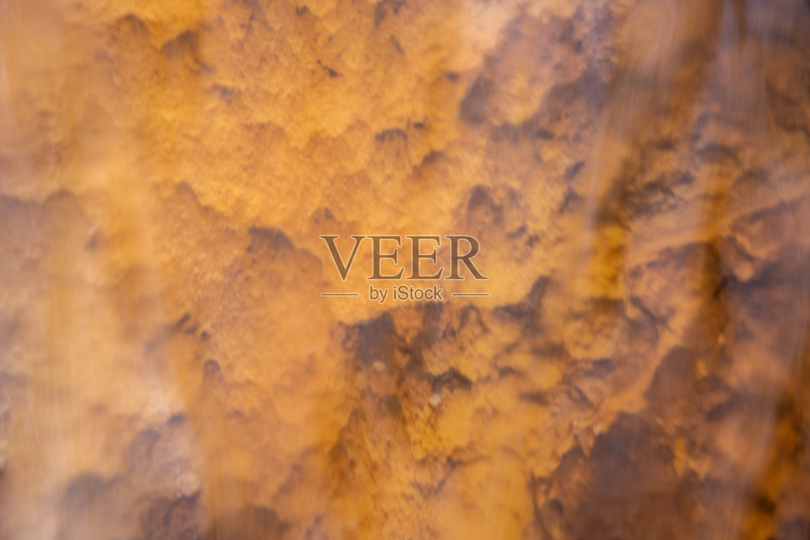 穿过湍急的水流的橙色岩石的粗糙纹理照片摄影图片