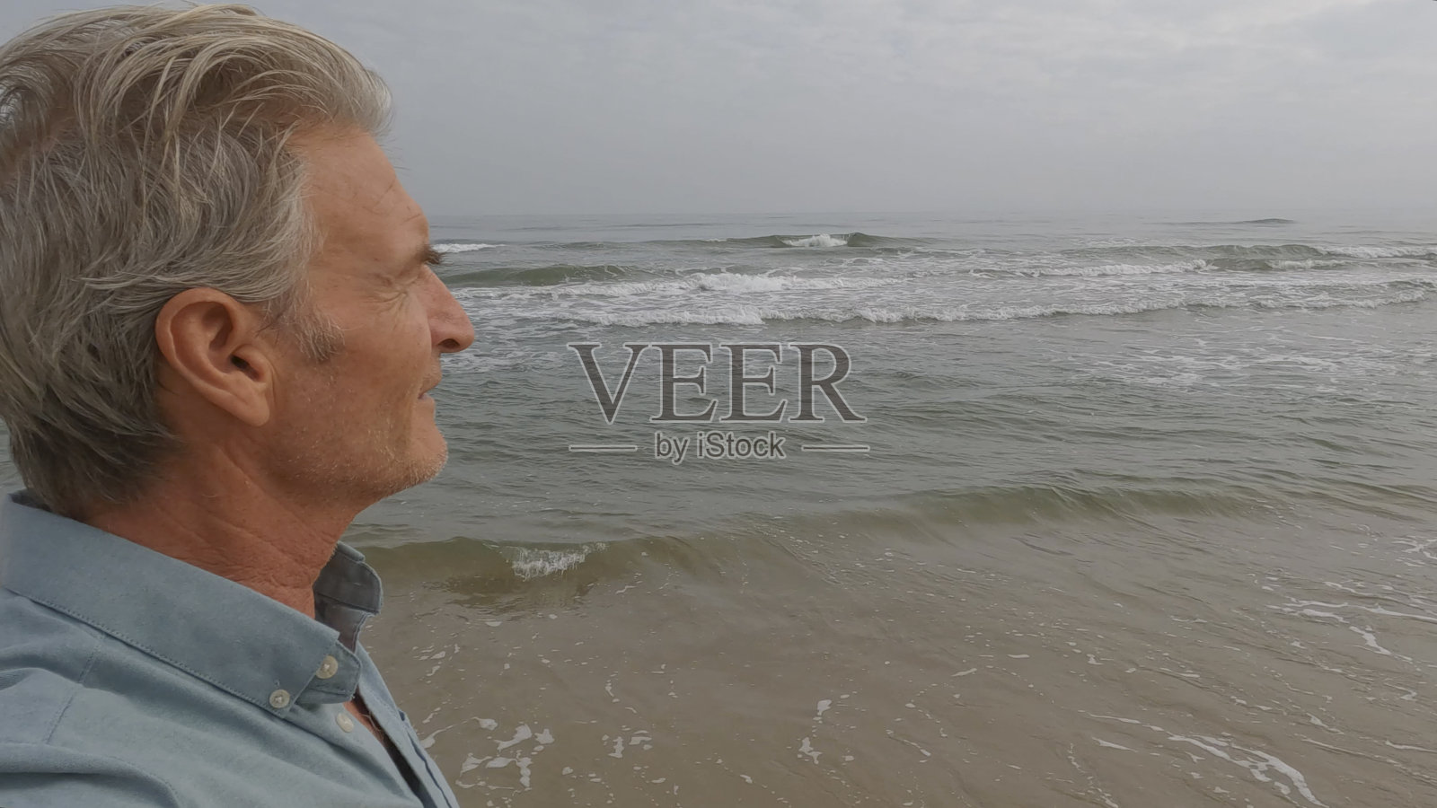 一个成熟的男人看着海滩上的日出照片摄影图片