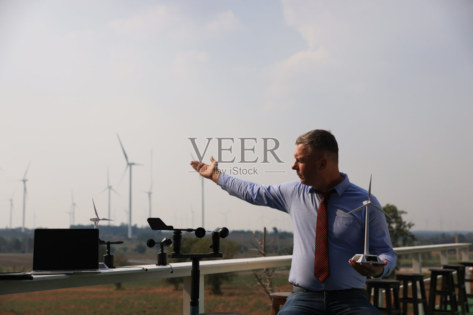 图为,一位资深男性能源专家正在风车内用风速测量仪检查生态建设工程中的风力发电机。照片摄影图片