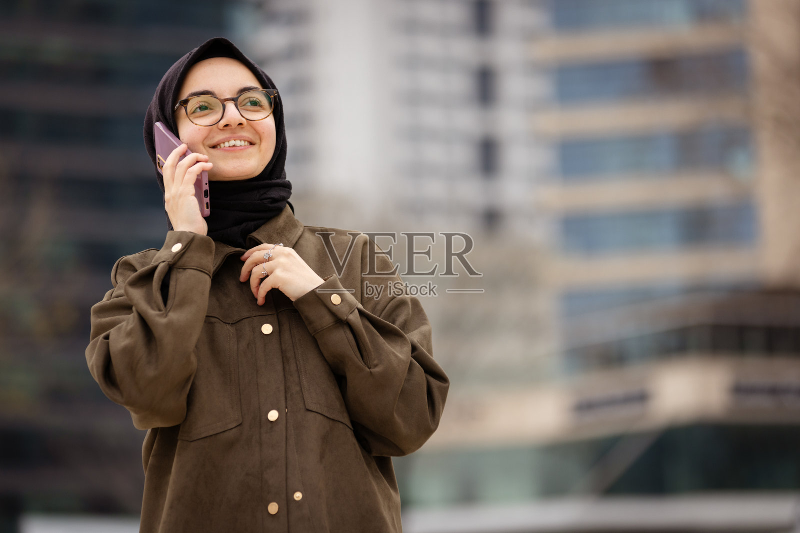 在街上用手机交谈的戴头巾的年轻女子照片摄影图片