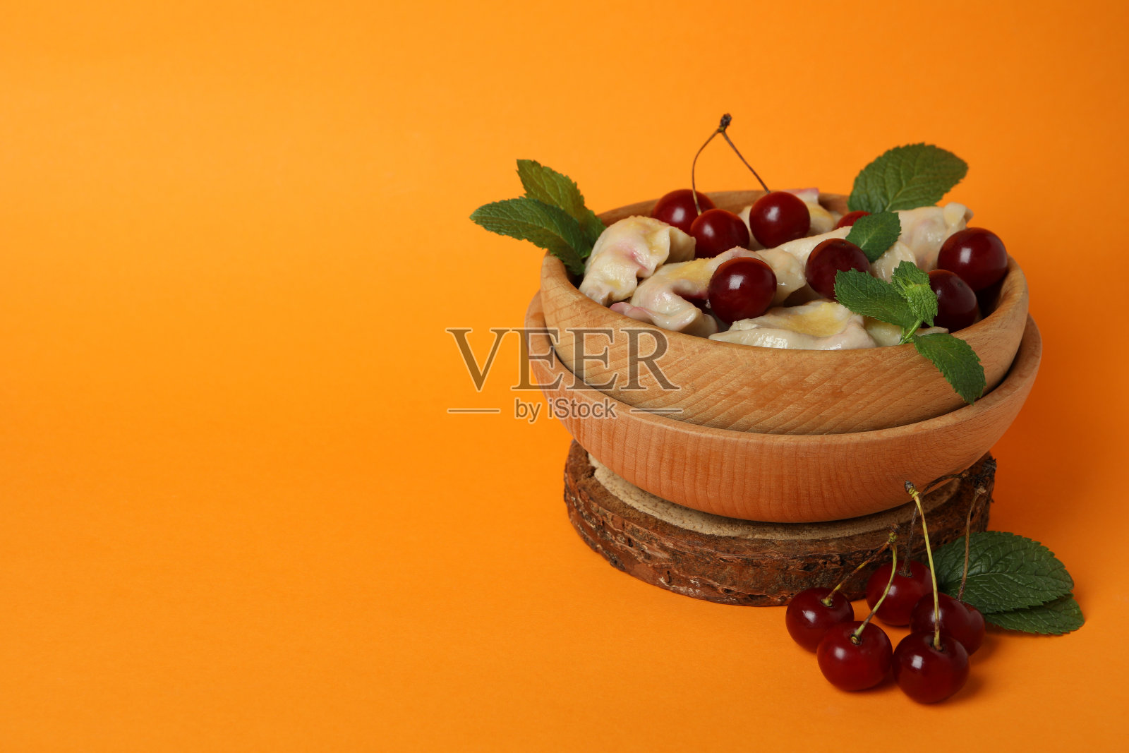 木制碗与樱桃在橙色背景pierogi照片摄影图片