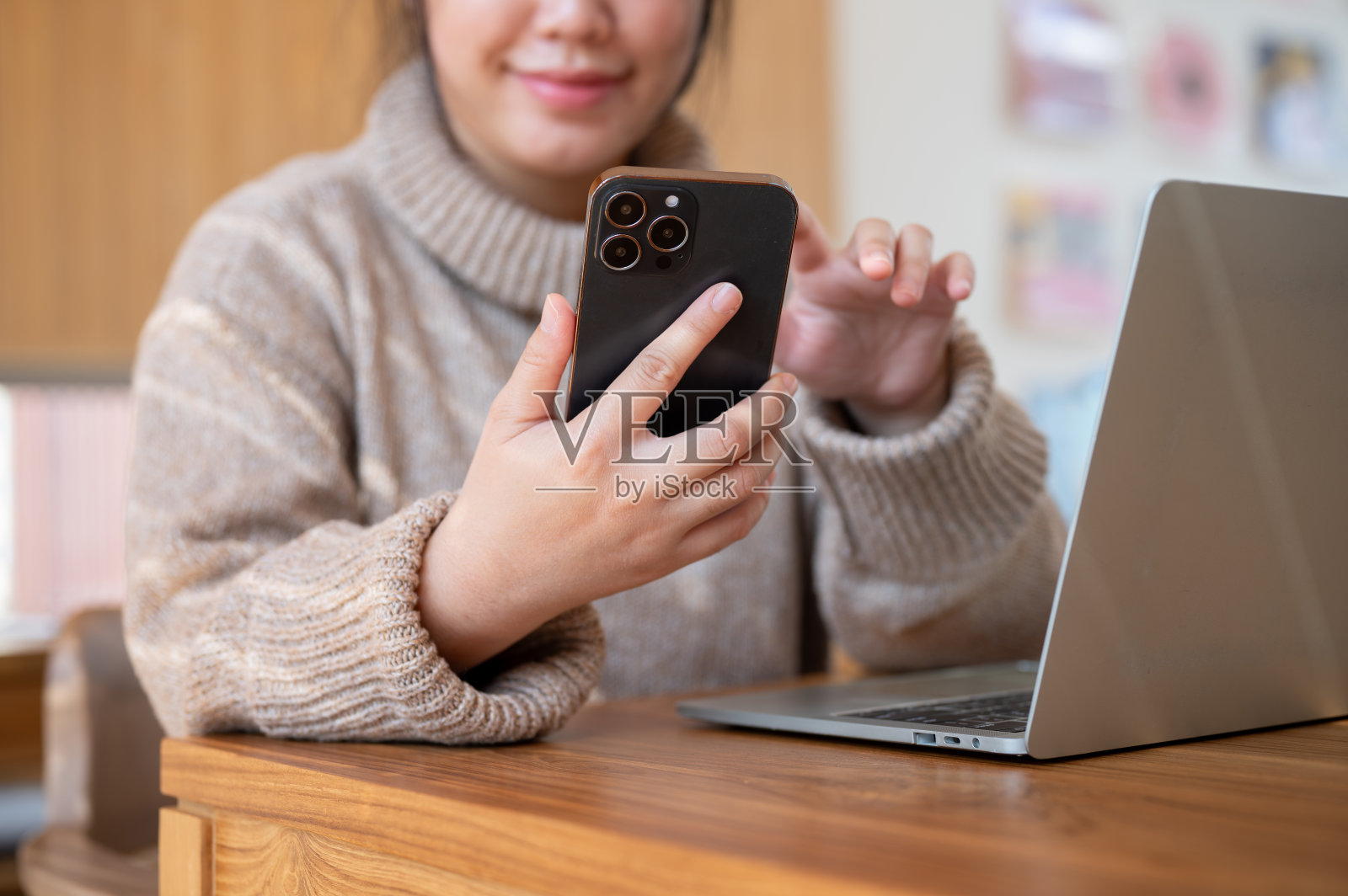 一位积极向上的亚洲女性在室内工作时查看手机信息的特写照片。照片摄影图片