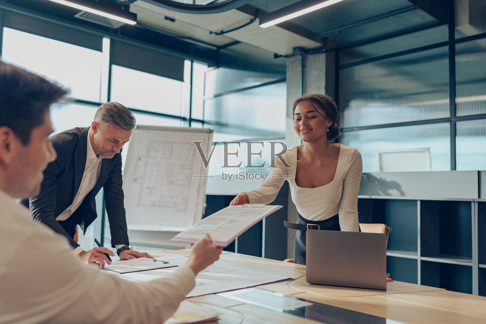 在活动挂图展示期间,女商人给工作小组成员分发材料照片摄影图片