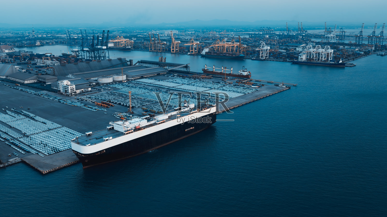 滚装船汽车运输车,新车在港口排队出口到世界各地的经销商。commercialport背景。蓝色调电影风格照片摄影图片