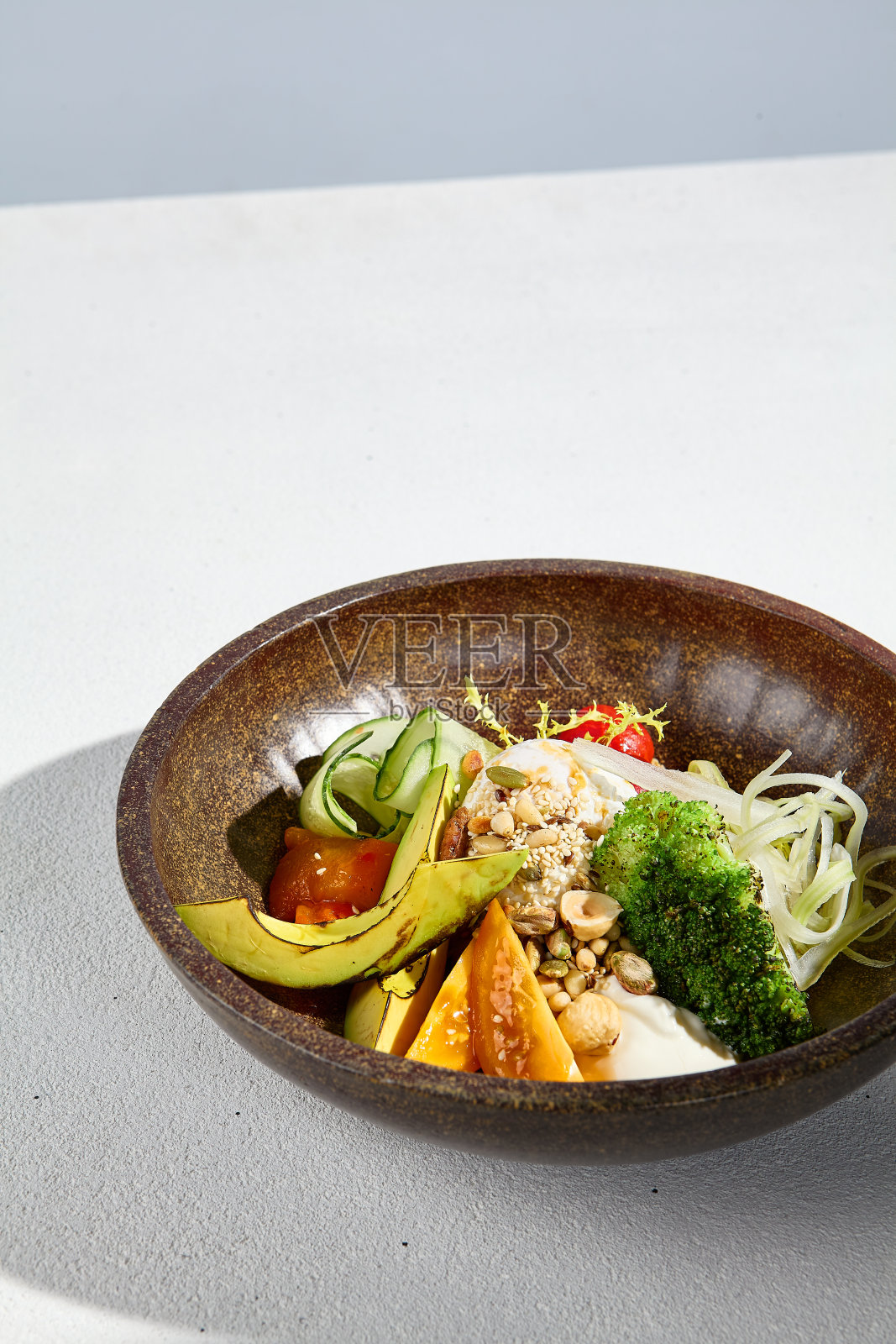 在明亮的阳光下,用鳄梨、混合蔬菜和荷包蛋做的沙拉碗照片摄影图片