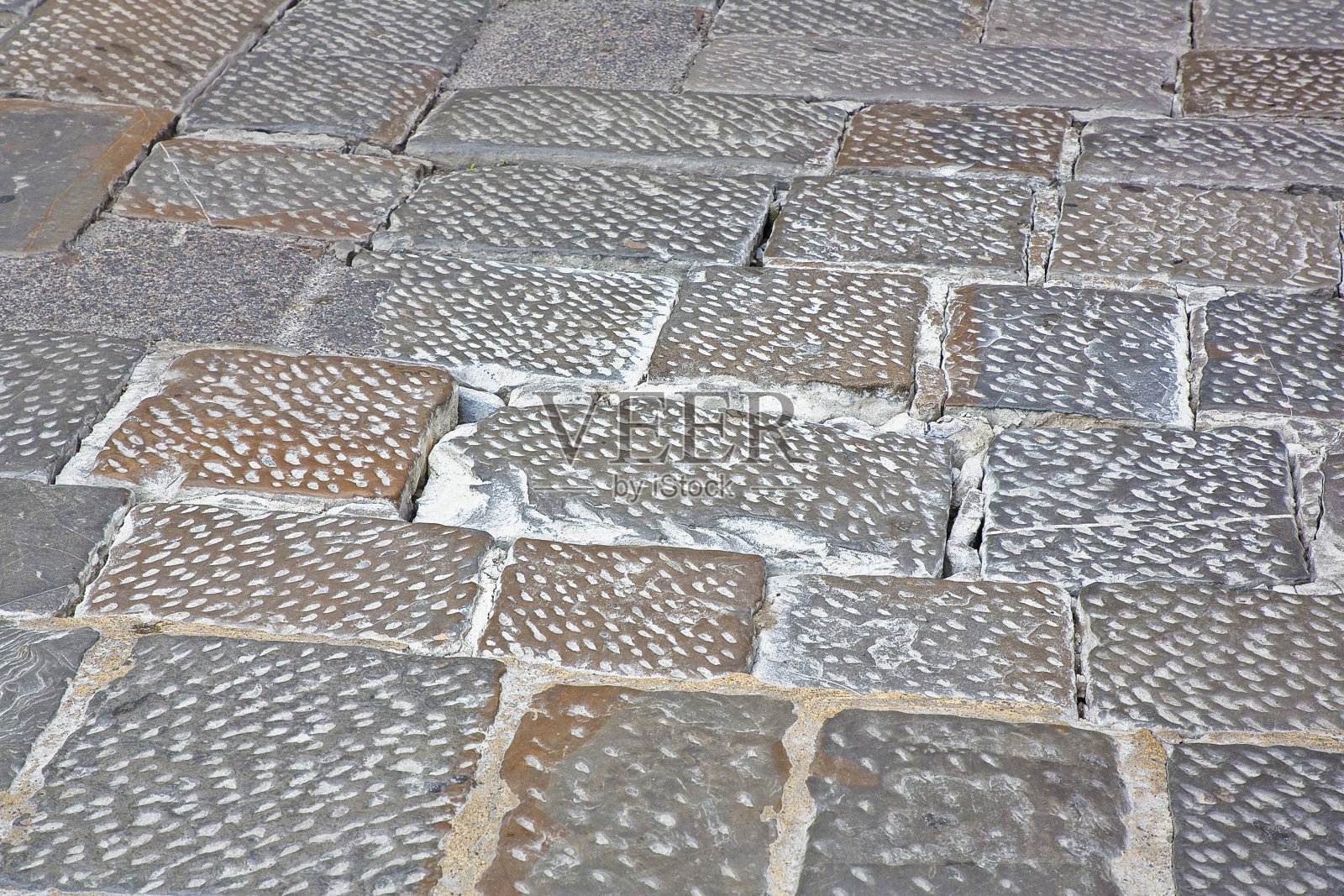 ▽步行区用砂石砌块铺成的陈旧、破损的路面=由于车辆的通行,路面部分出现了破损照片摄影图片