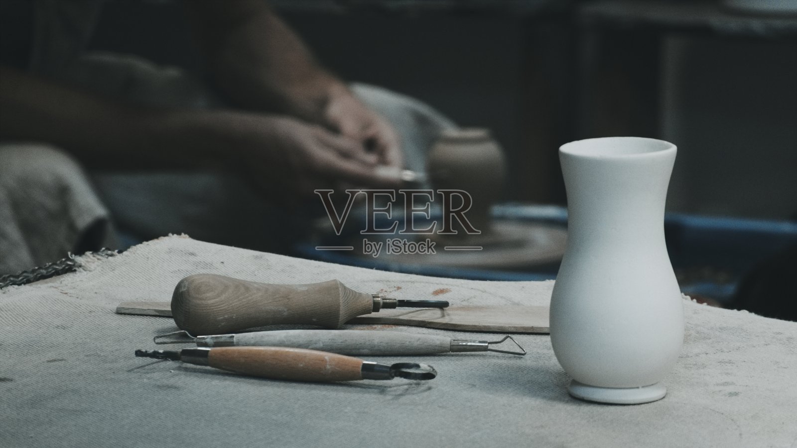 雕塑家工作场景:白色花瓶、陶艺工具和陶艺师的手照片摄影图片