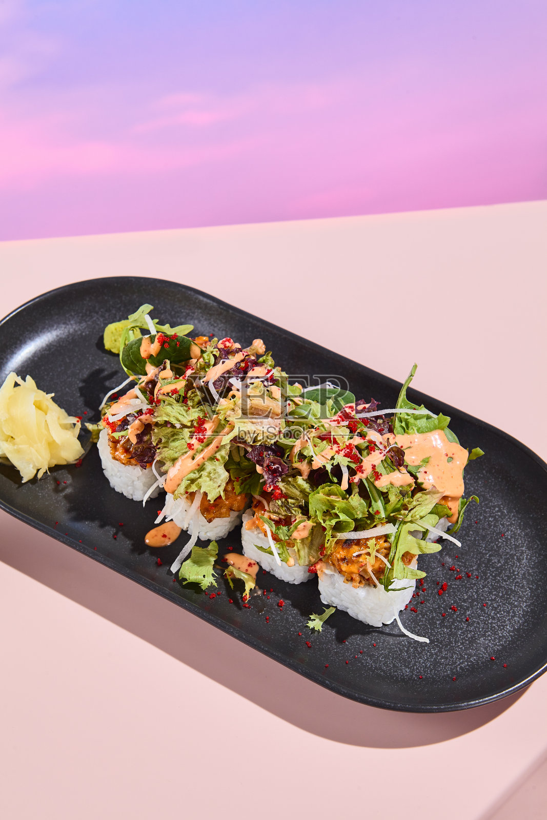 三文鱼卷寿司配上沙拉,优雅地放在黑色盘子里,以超现实的春夏花香为主题照片摄影图片