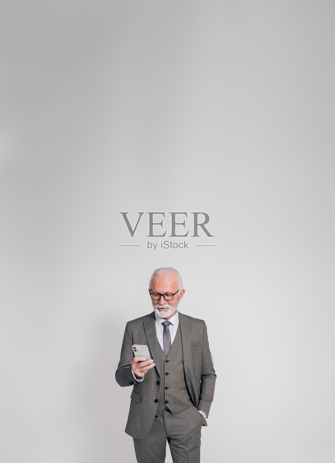 高级商人的肖像,手放在口袋里,在白色背景的智能手机上发短信照片摄影图片