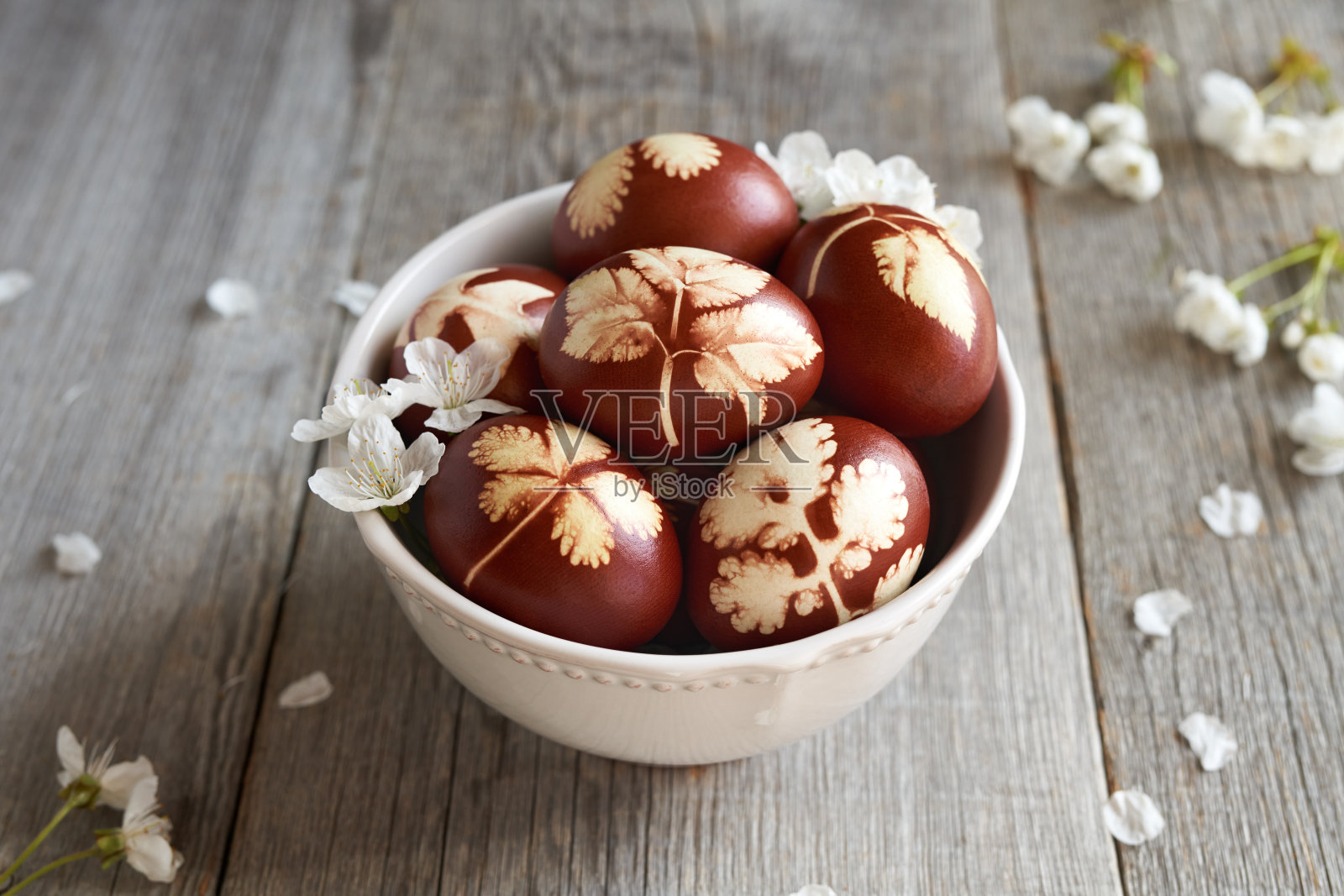 棕色的复活节用洋葱皮染成一个碗里的新鲜树叶图案,还有白色的樱花照片摄影图片