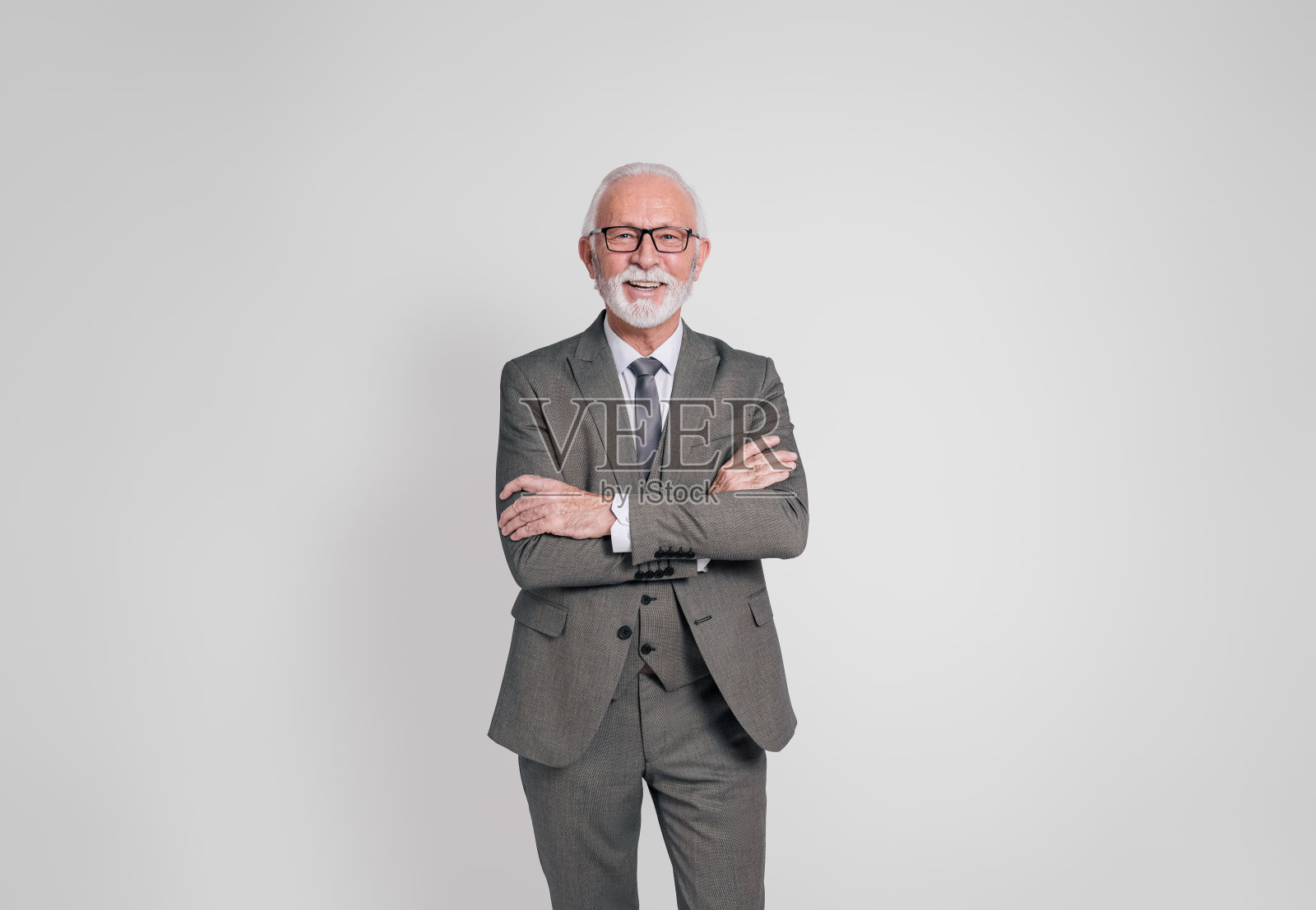 在白色背景上,一位面带微笑、自信的年长商人双臂交叉站着照片摄影图片