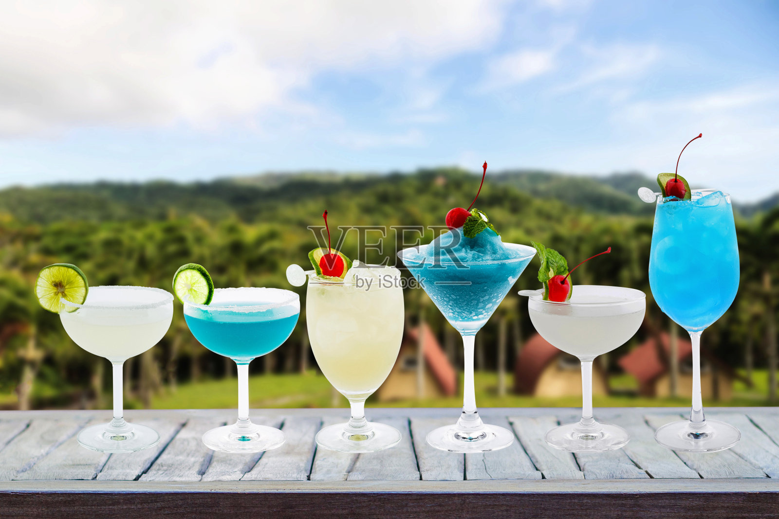 色彩缤纷的夏日鸡尾酒在玻璃杯里,鸡尾酒在木桌和露营自然景观的背景下,假期旅行的想法与节日聚会庆祝成功有酒照片摄影图片