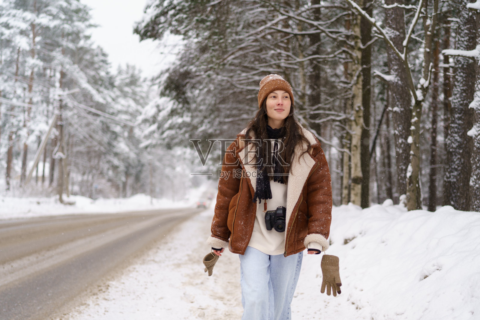 年轻快乐的亚洲女性旅游博主,脖子上挂着相机,漫步在雪道上照片摄影图片