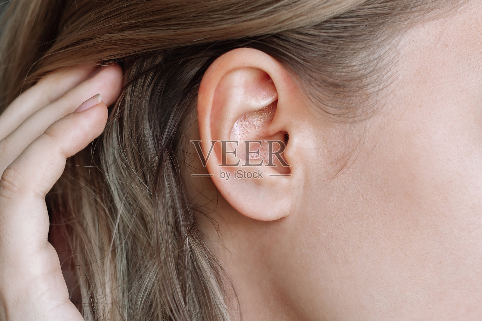 一个长着黑头的女人耳朵的特写。痘痘问题,闭合性粉刺。毛孔粗大照片摄影图片