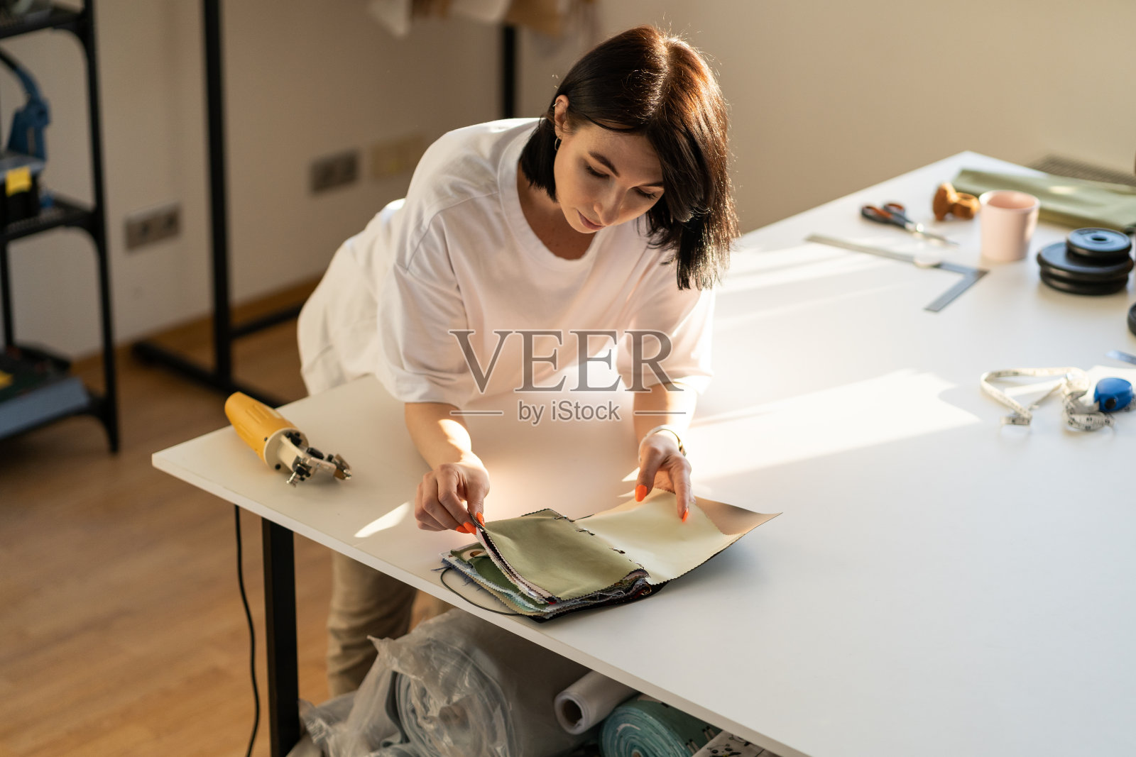 裁缝在时装车间挑选布料。下水道时装设计师拿着布样书照片摄影图片