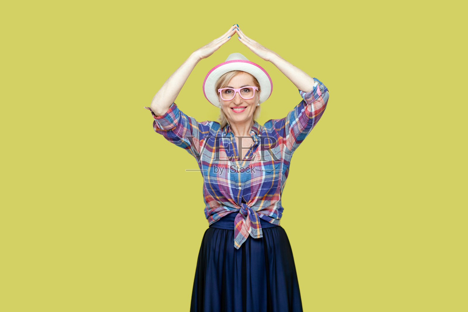 积极开朗快乐的老年妇女在头顶上比划着屋顶符号,感觉受到了保护。照片摄影图片