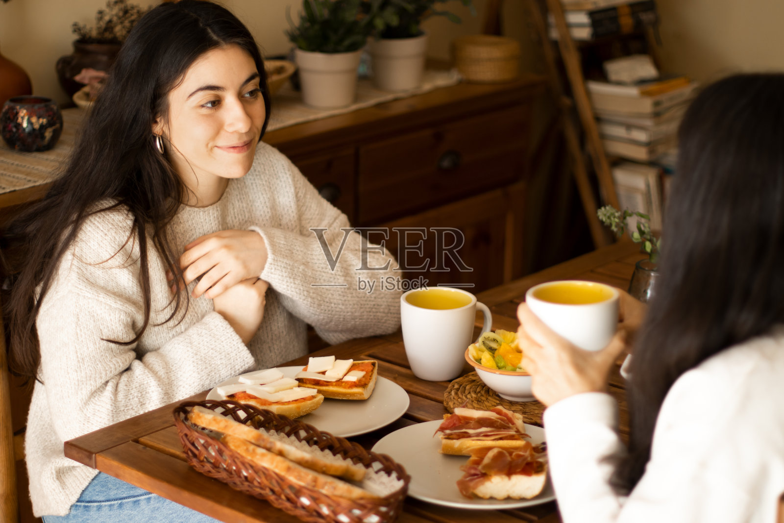 美丽的年轻女子和她妈妈一起吃早餐。照片摄影图片