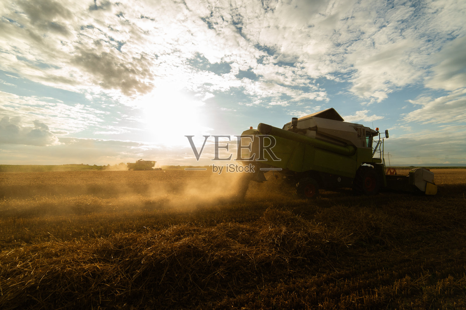 夕阳下在麦田里工作的收割机。照片摄影图片