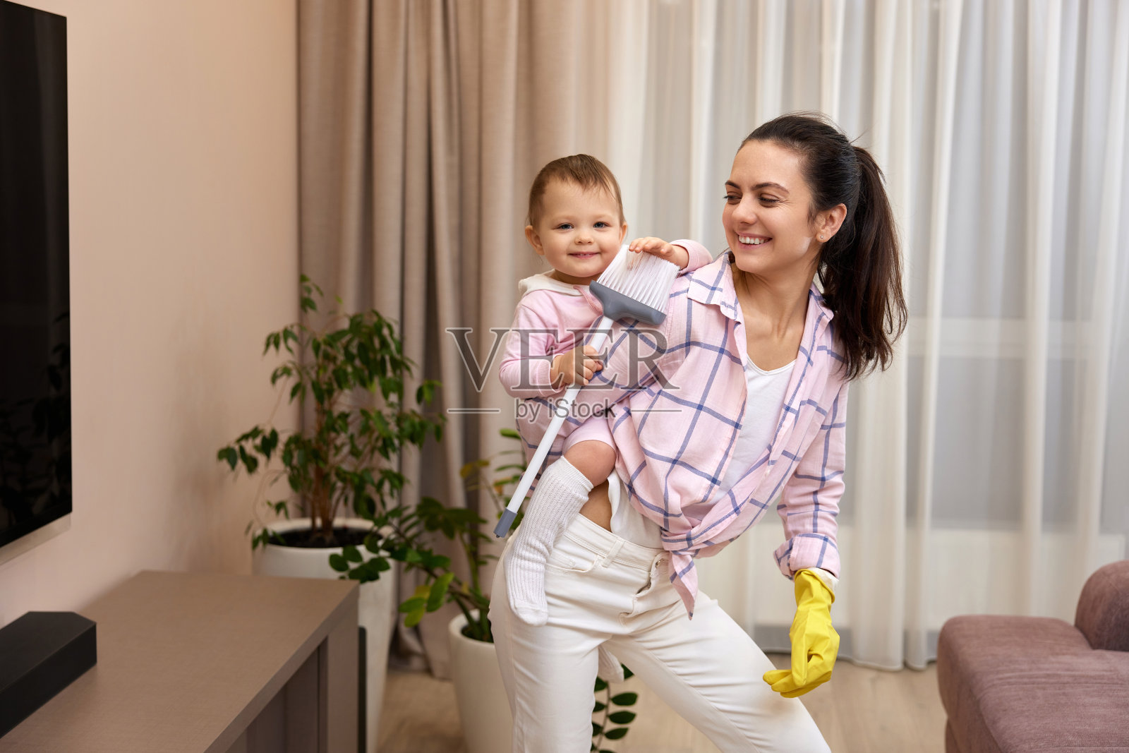 家庭主妇抱着孩子做家务照片摄影图片