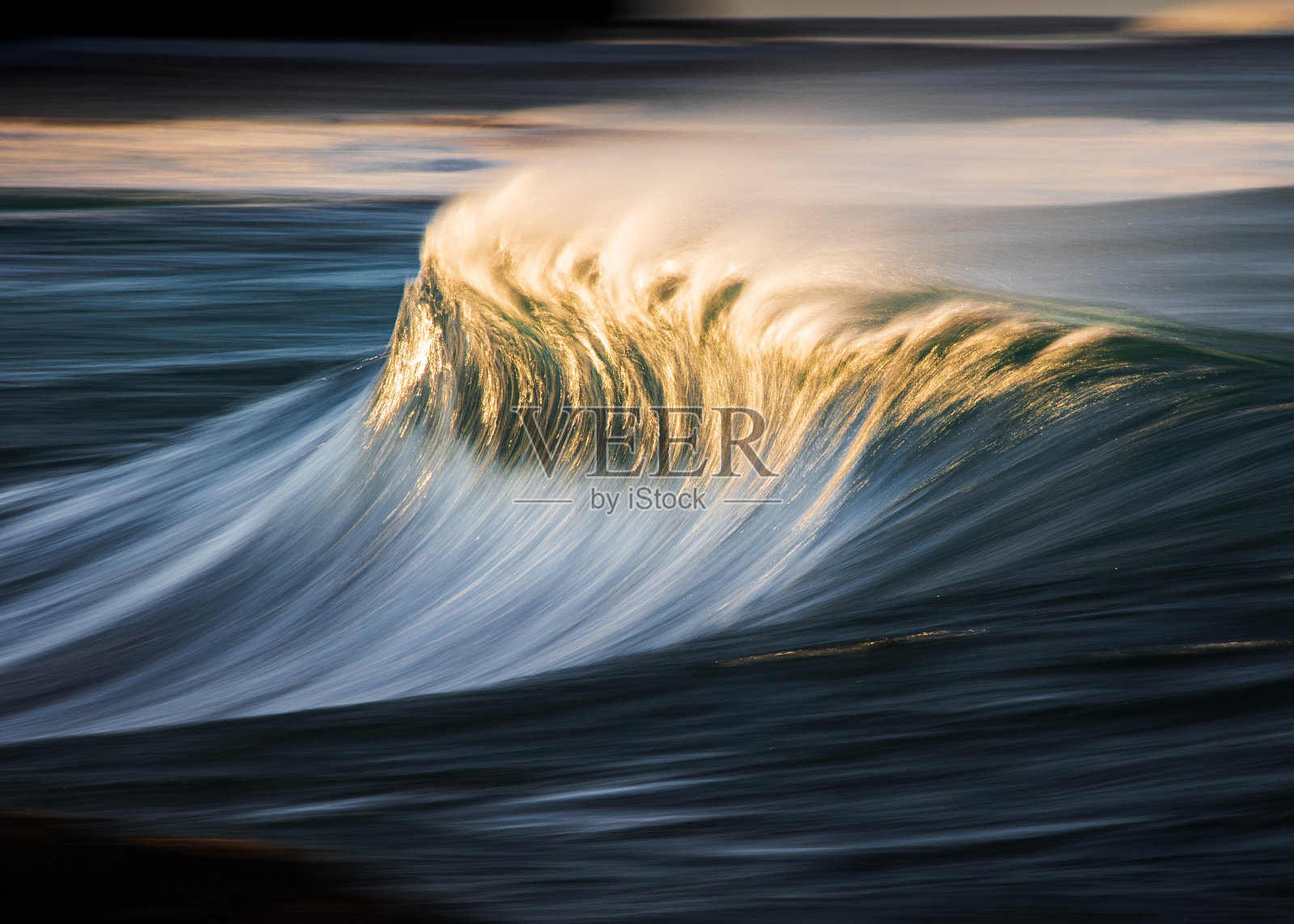 缓慢的快门模糊的平滑波浪打破礁石在海洋与戏剧性的金色光照片摄影图片