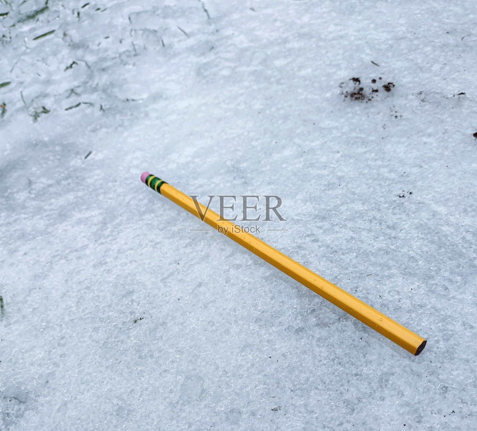 一只黄色铅笔在冰冷的地面上照片摄影图片