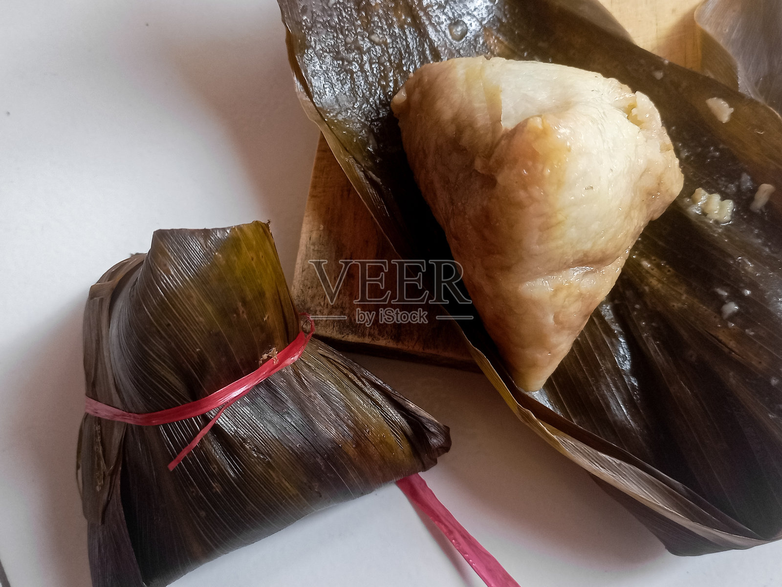 粽子或八仓。用竹叶包着的中国香糯粽子,一个被切成两半。照片摄影图片