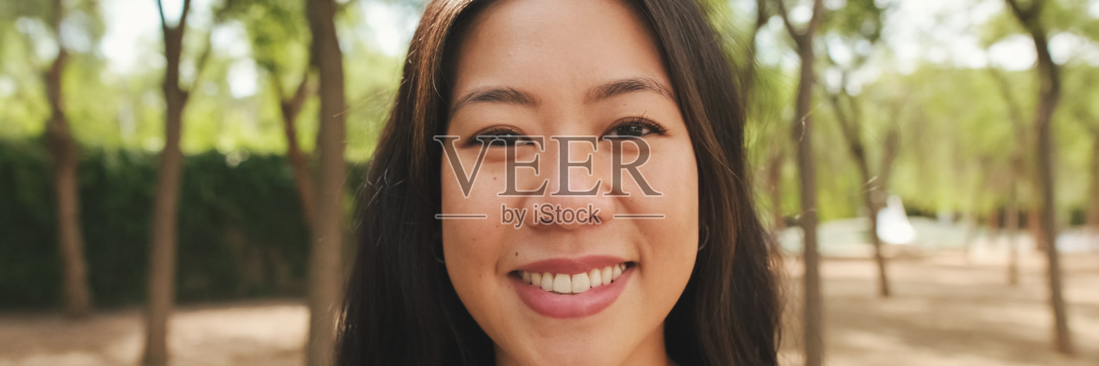 身穿白色上衣和牛仔裤的黑发女孩微笑着看着镜头的特写,全景照片摄影图片