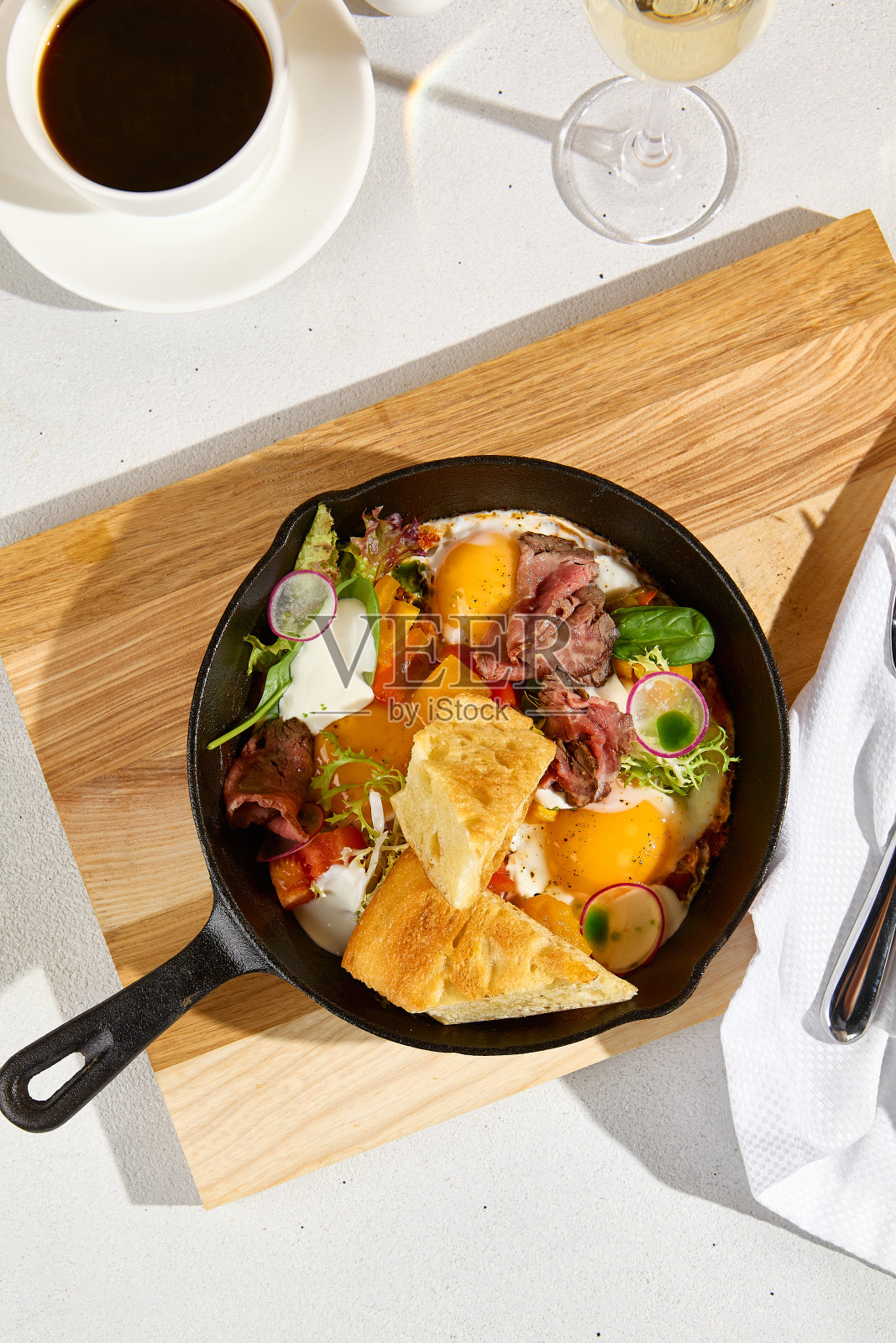煎蛋在煎锅与烤牛肉,蔬菜,和意大利面包,美式咖啡,和一杯起泡酒,顶视图照片摄影图片