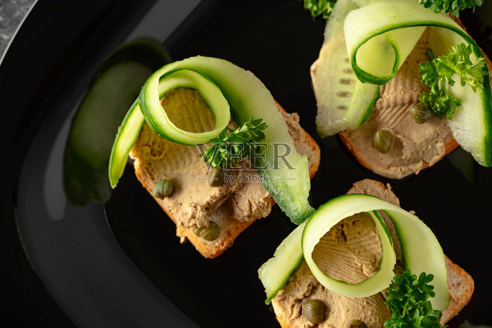 开放式三明治配肉酱、新鲜黄瓜、刺山柑和欧芹。照片摄影图片