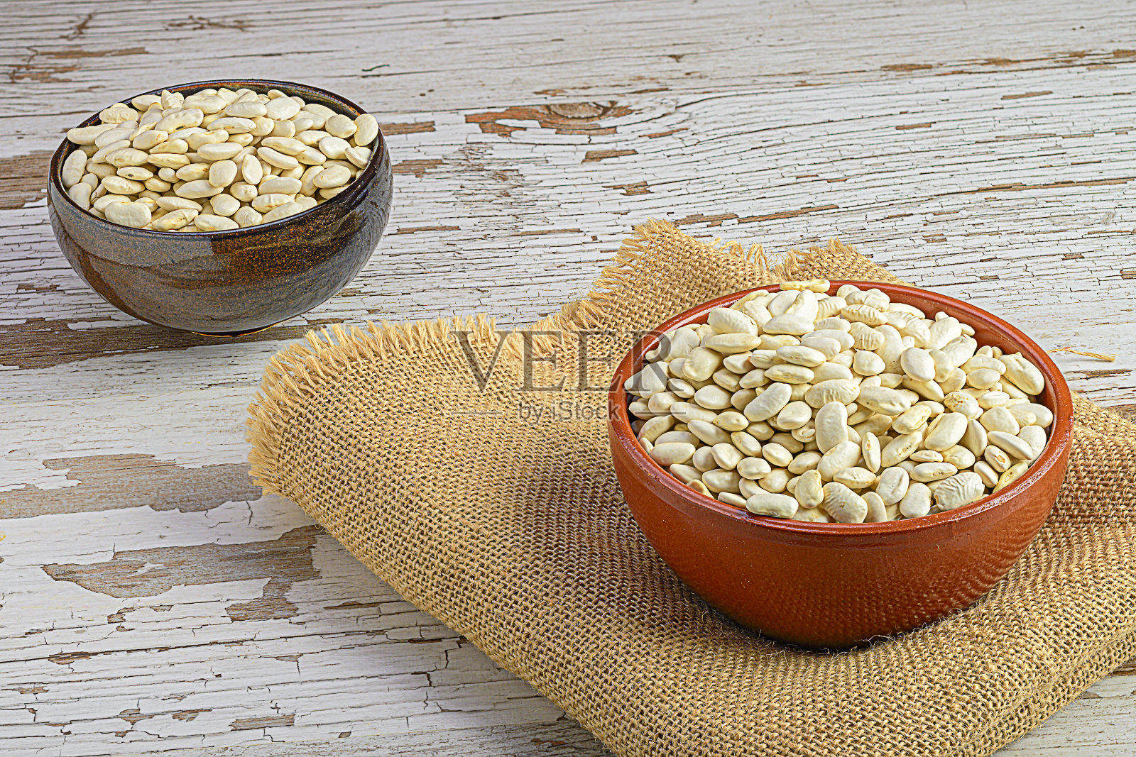 乡村厨房场景:红色和黑色的碗与白豆木制背景照片摄影图片