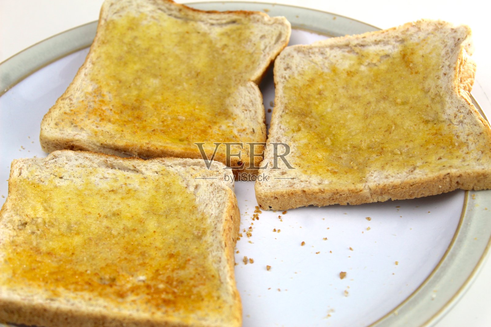 白色盘子里放着三片涂了黄油的吐司照片摄影图片