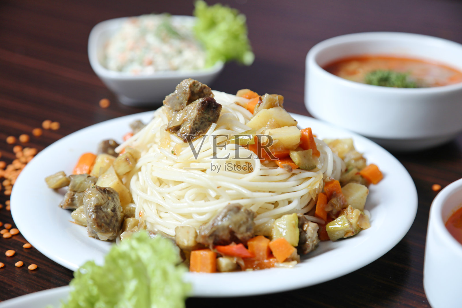 桌子展示了各种盘子的食物和碗的汤。照片摄影图片