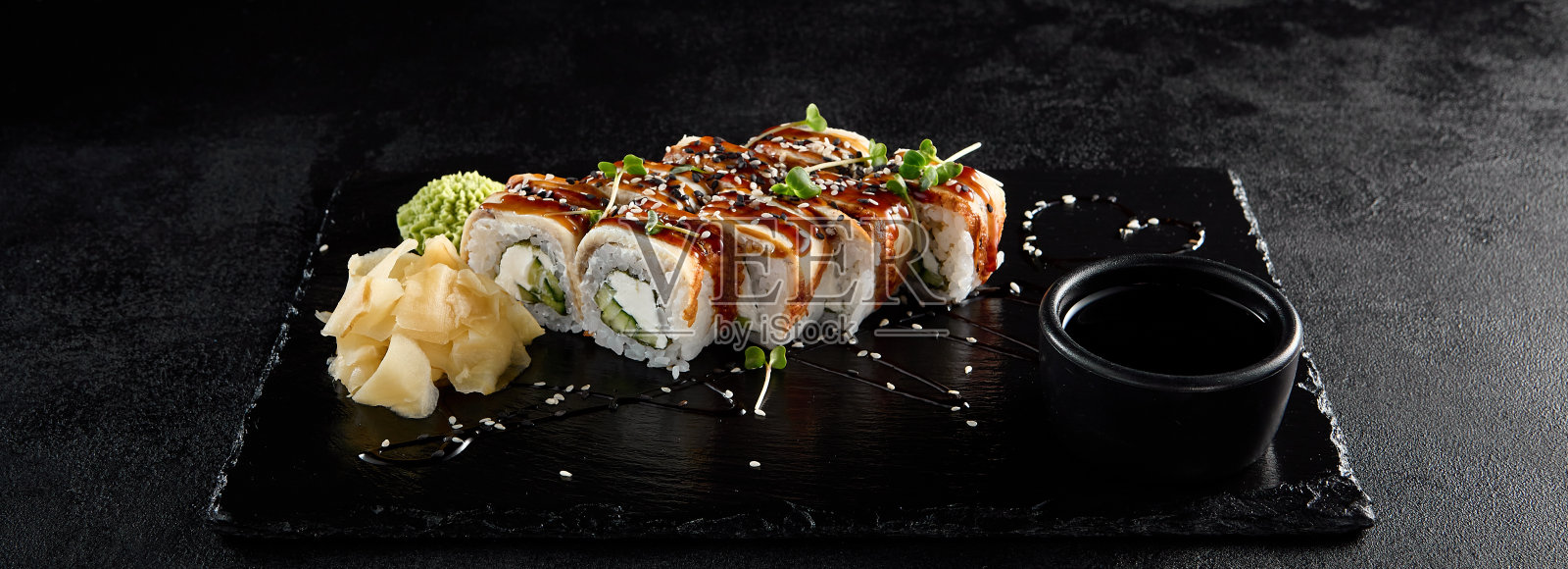 加拿大卷配鳗鱼和鲣鱼酱,与酱油和芥末一起放在黑石板上照片摄影图片